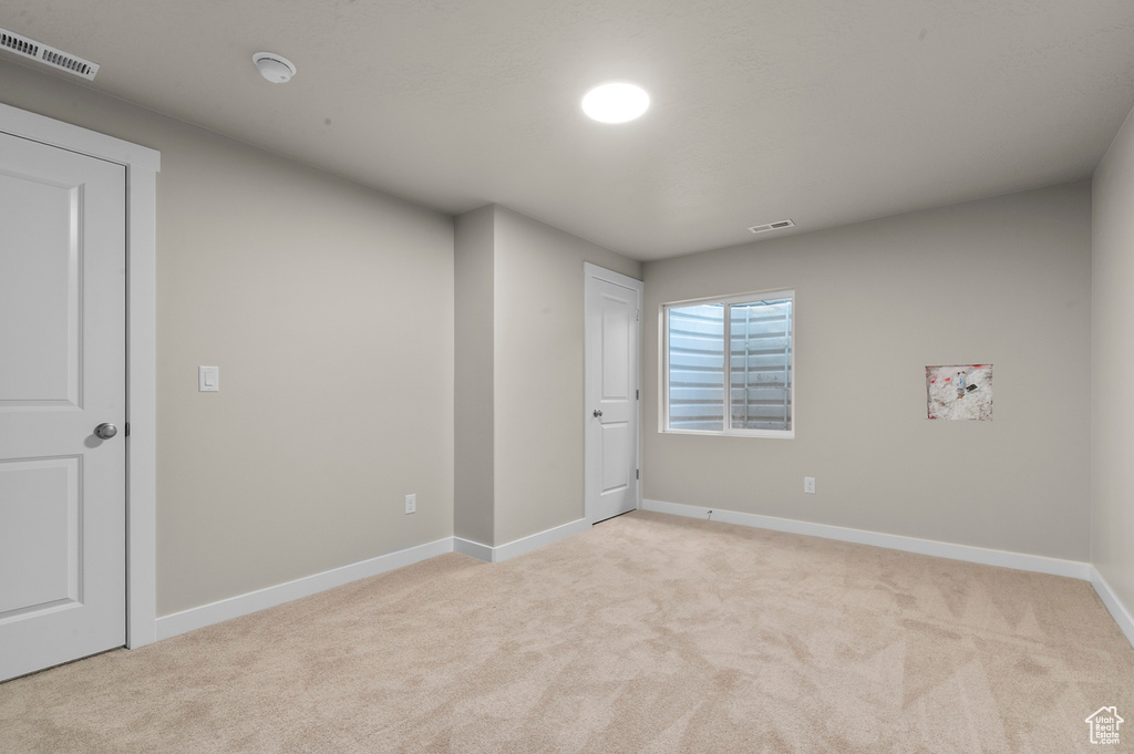 Empty room with light colored carpet, baseboards, and visible vents