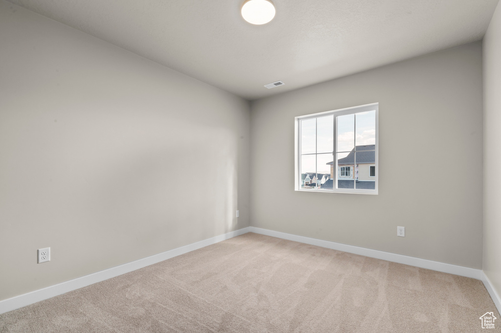 Carpeted empty room featuring baseboards and visible vents