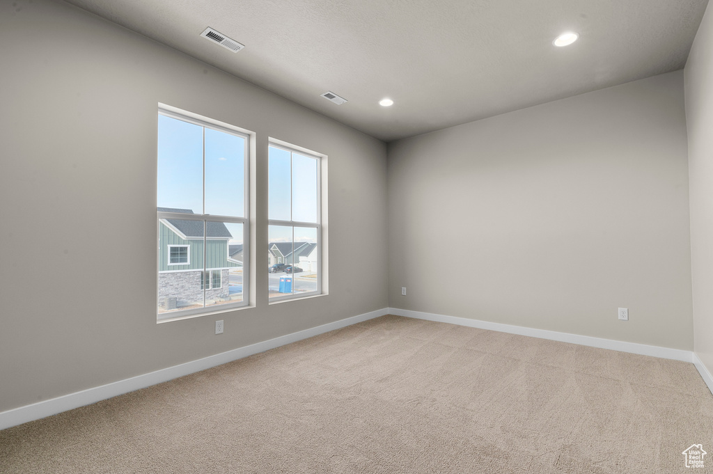 Spare room with visible vents, recessed lighting, baseboards, and light carpet