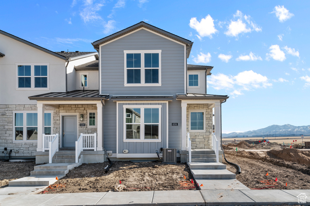 View of front of property with stone siding, a mountain view, cooling unit, a standing seam roof, and metal roof