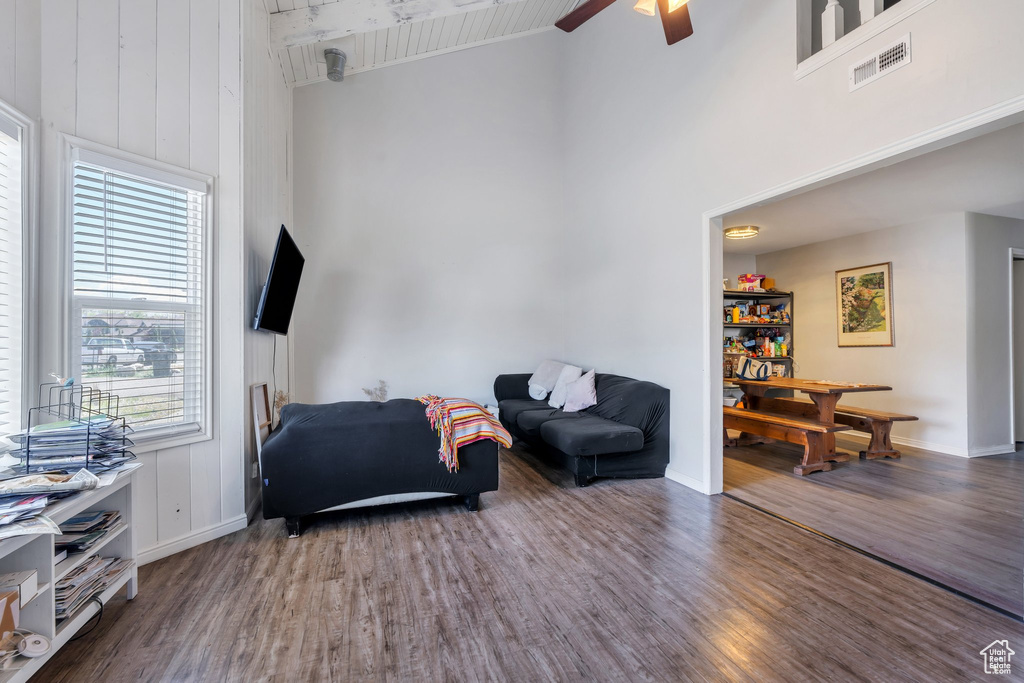Living room with high vaulted ceiling, baseboards, wood finished floors, beamed ceiling, and visible vents