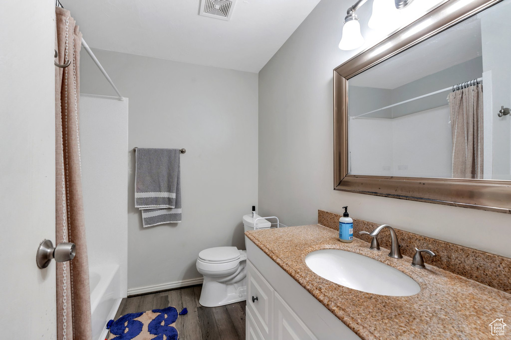 Bathroom with visible vents, vanity, wood finished floors, toilet, and baseboards