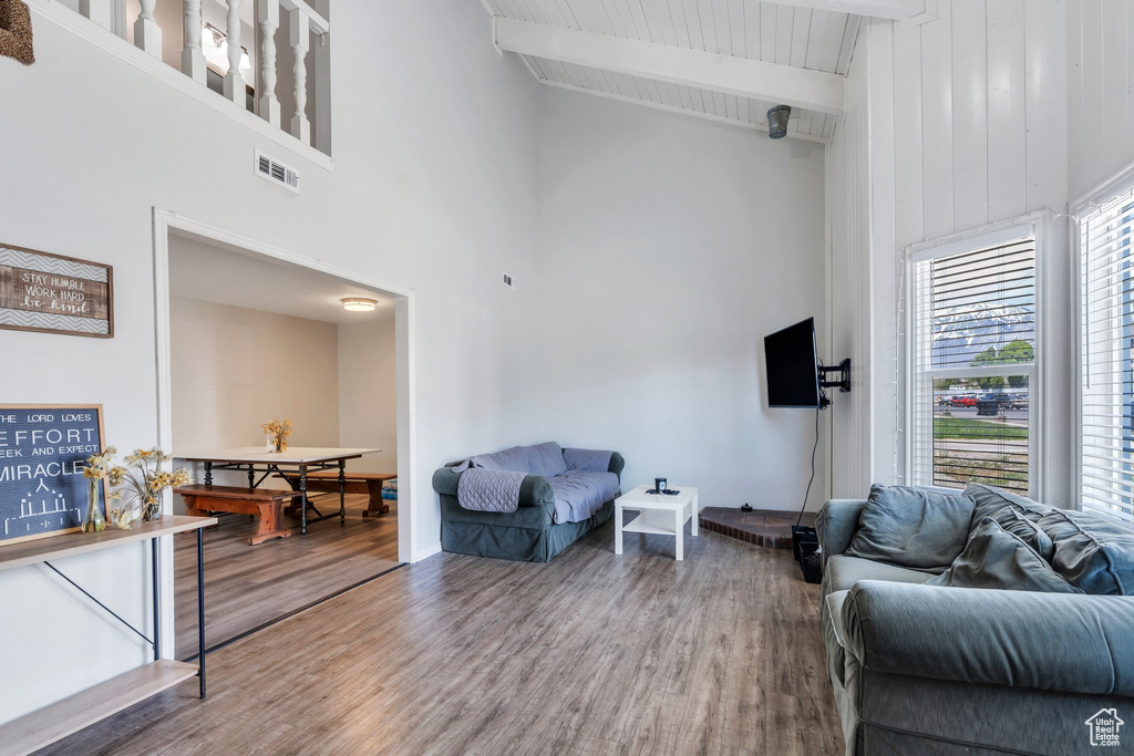 Living area with high vaulted ceiling, beamed ceiling, wood finished floors, and visible vents