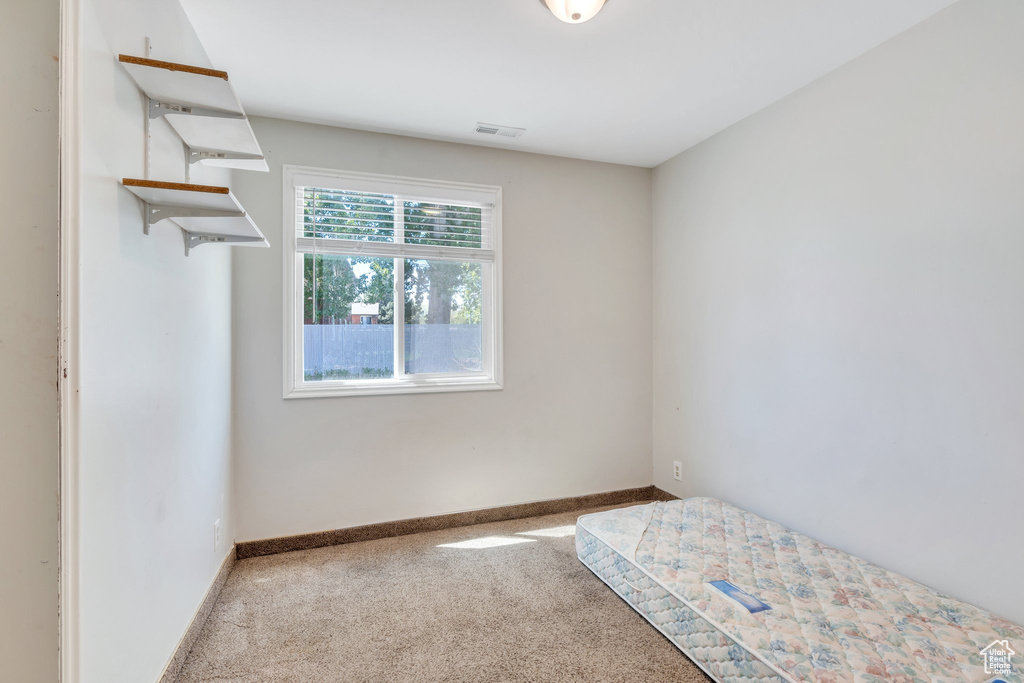 Unfurnished bedroom with carpet floors, baseboards, and visible vents