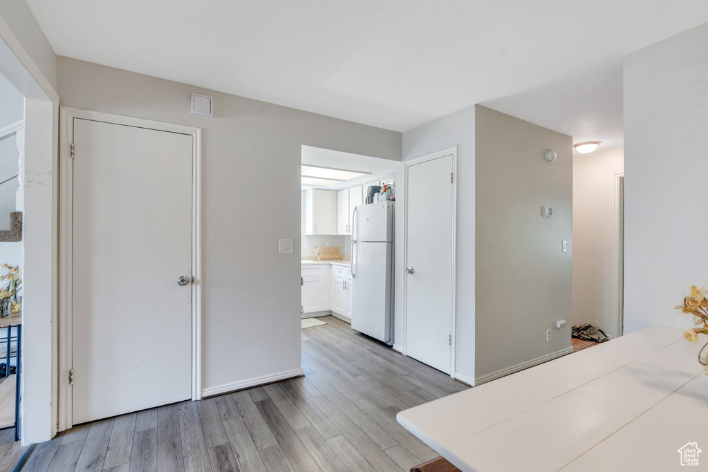 Interior space with light wood-style floors, freestanding refrigerator, and connected bathroom