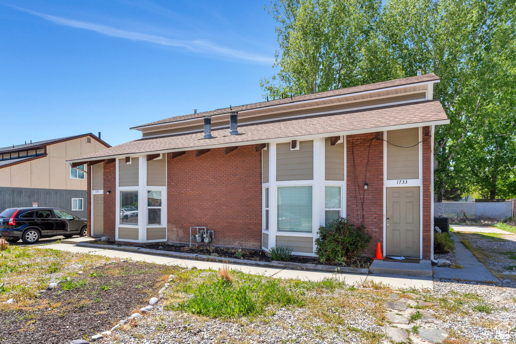 Single story home featuring brick siding, roof with shingles, and fence