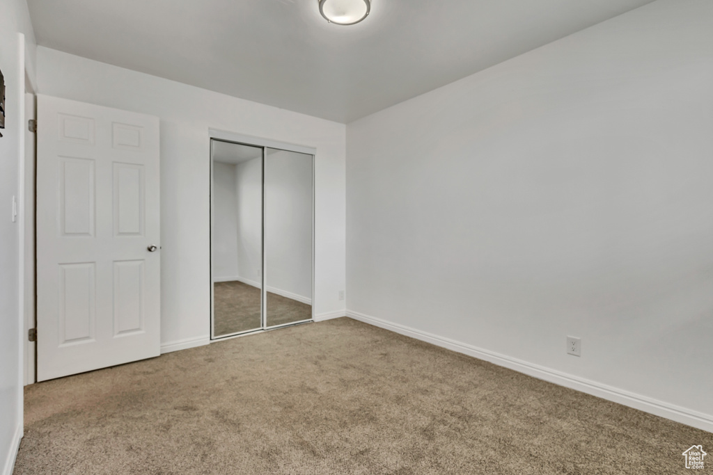 Unfurnished bedroom featuring baseboards, carpet flooring, and a closet