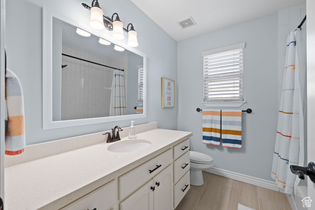 Full bathroom with a shower with curtain, baseboards, visible vents, and vanity