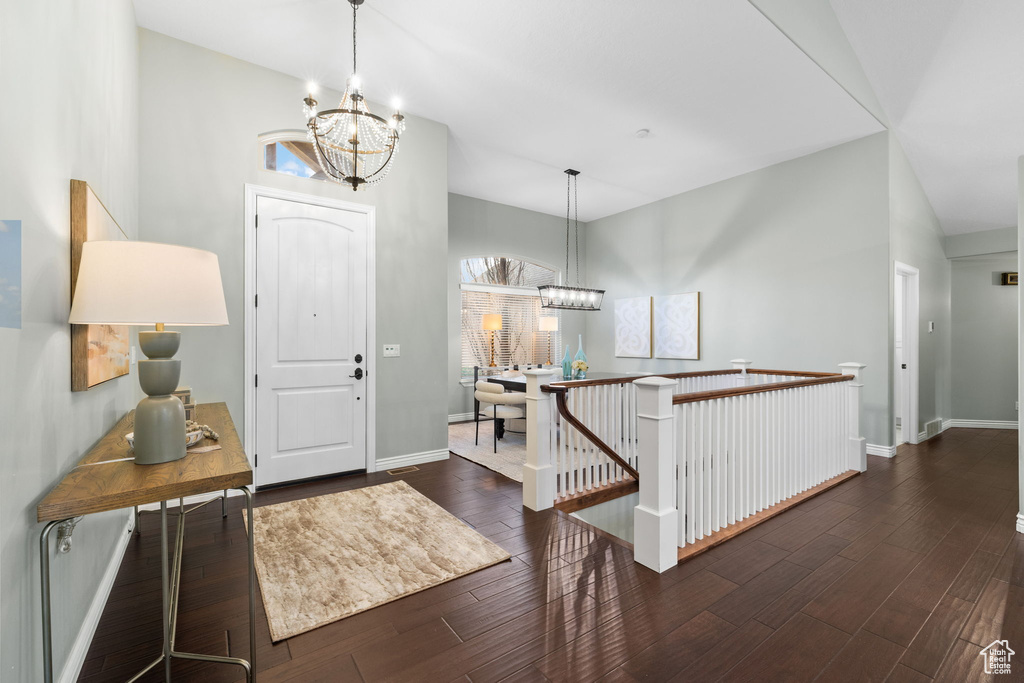 Foyer with baseboards, a chandelier, and dark wood-style flooring