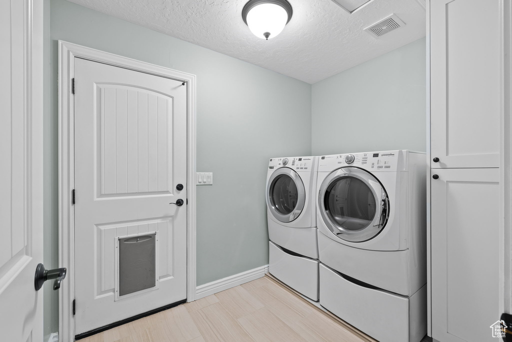 Laundry area with laundry area, visible vents, baseboards, separate washer and dryer, and a textured ceiling