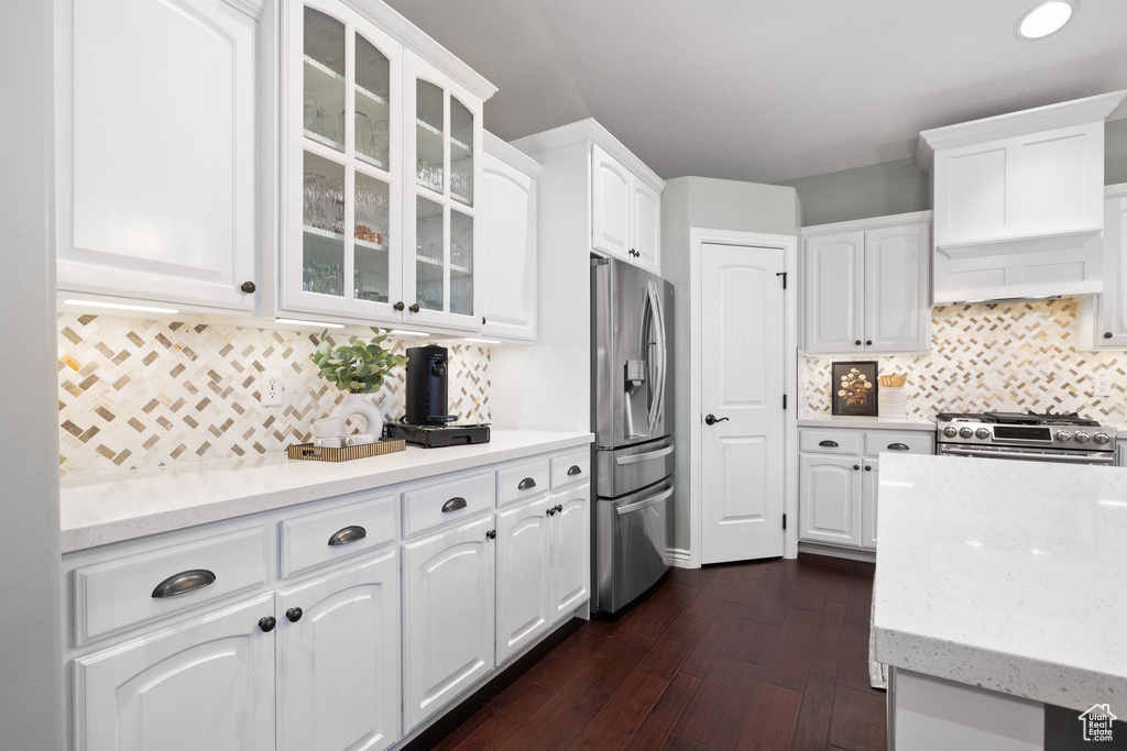Kitchen featuring dark wood-style flooring, appliances with stainless steel finishes, white cabinetry, and glass insert cabinets