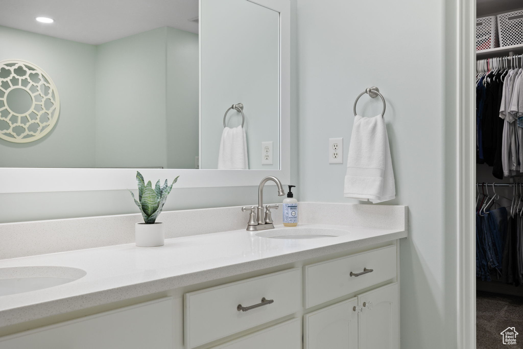 Full bath with a spacious closet, a sink, recessed lighting, and double vanity