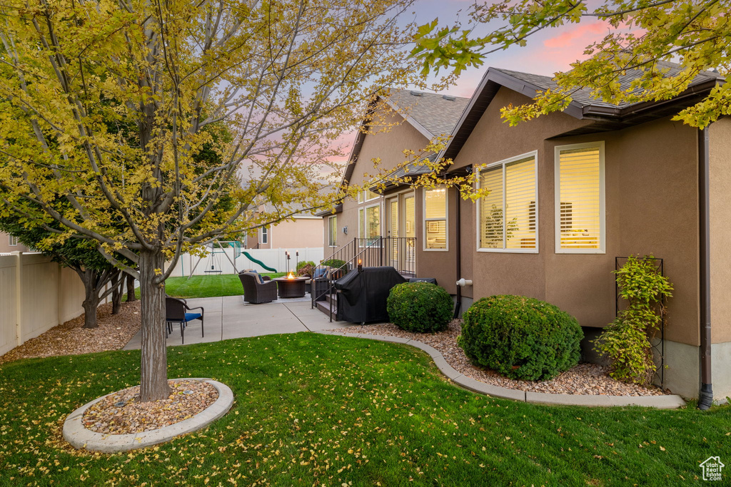 Yard at dusk with a fenced backyard, an outdoor hangout area, and a patio