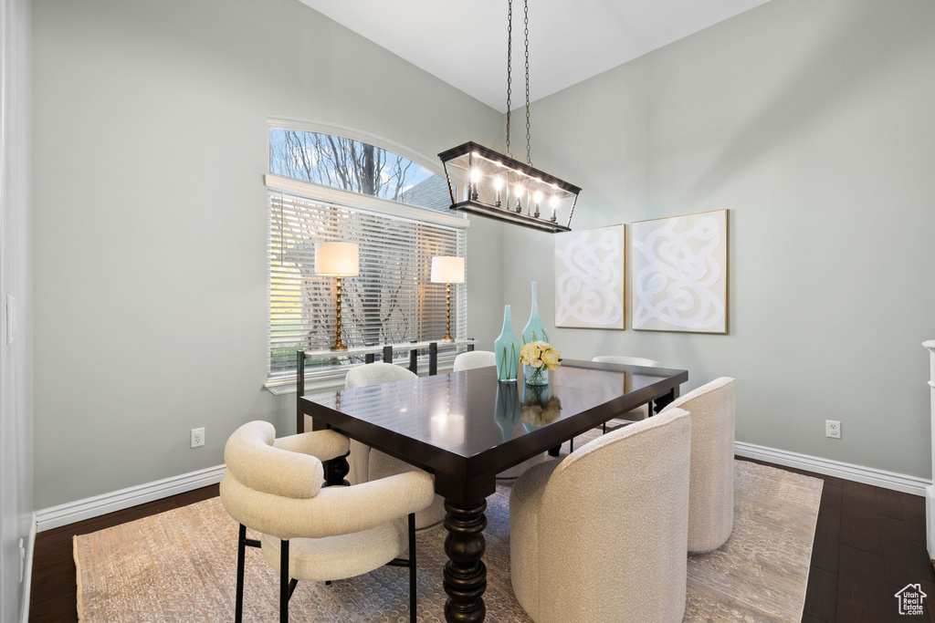 Dining room featuring a chandelier, wood finished floors, lofted ceiling, and baseboards
