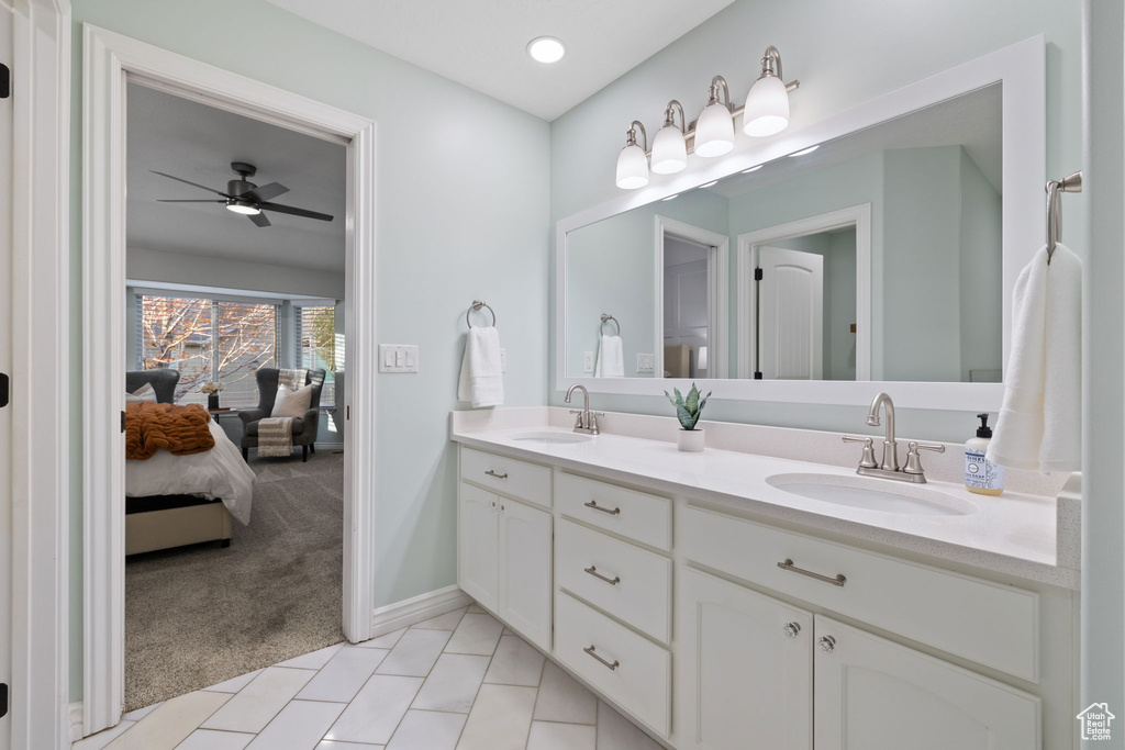 Bathroom with ceiling fan, baseboards, a sink, and double vanity