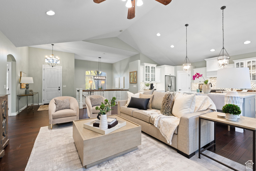 Living room with vaulted ceiling, wood finished floors, ceiling fan with notable chandelier, arched walkways, and recessed lighting
