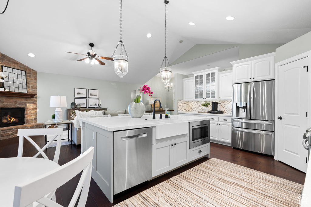 Kitchen with a sink, stainless steel appliances, white cabinetry, lofted ceiling, and dark wood-style flooring