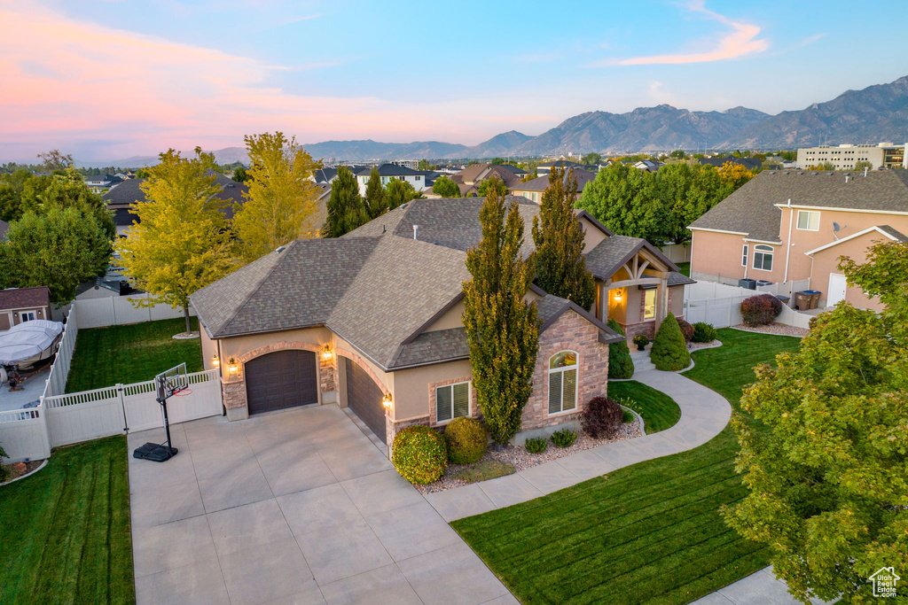 View of front of home with a gate, driveway, stone siding, an attached garage, and stucco siding
