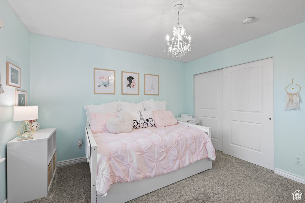 Carpeted bedroom featuring baseboards, an inviting chandelier, and a closet