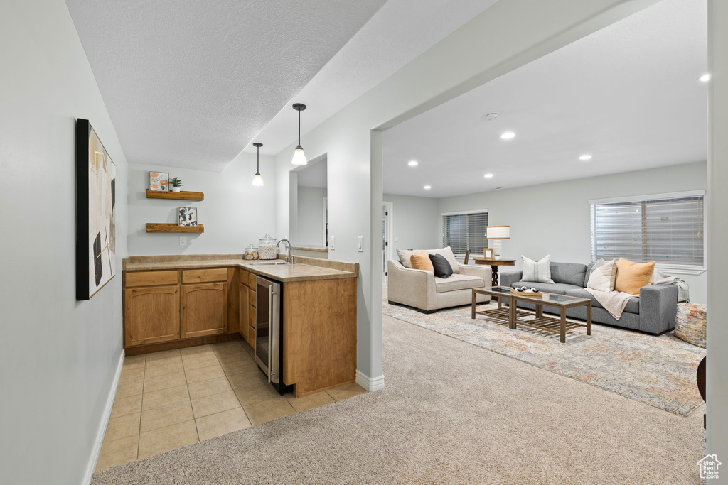 Kitchen featuring a sink, light carpet, light countertops, baseboards, and wine cooler