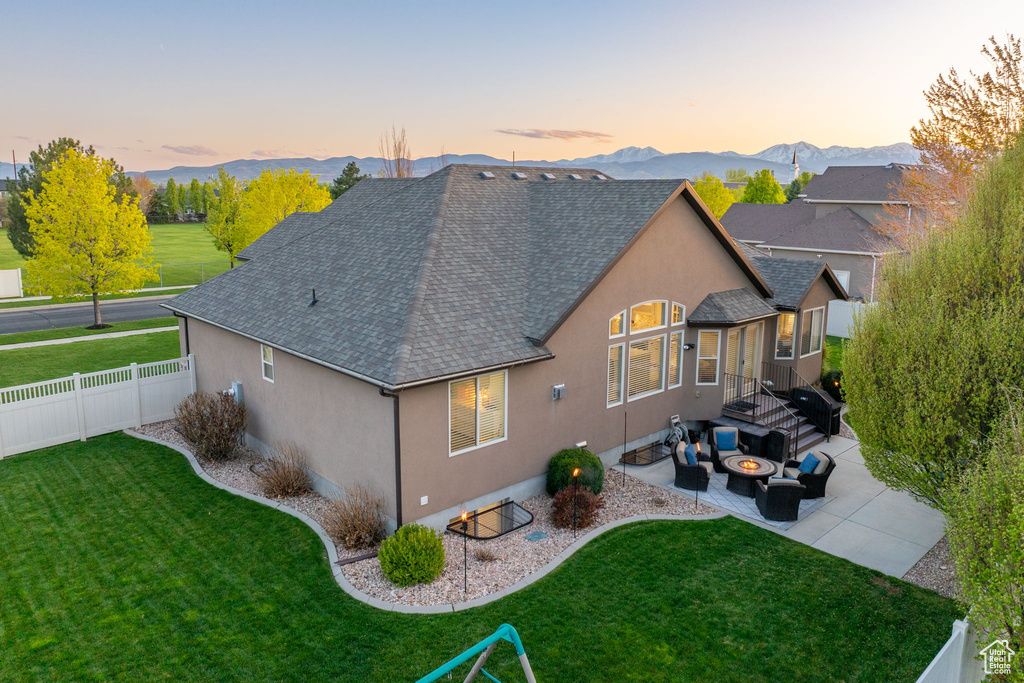 Back of house with roof with shingles, fence, a lawn, a patio, and stucco siding