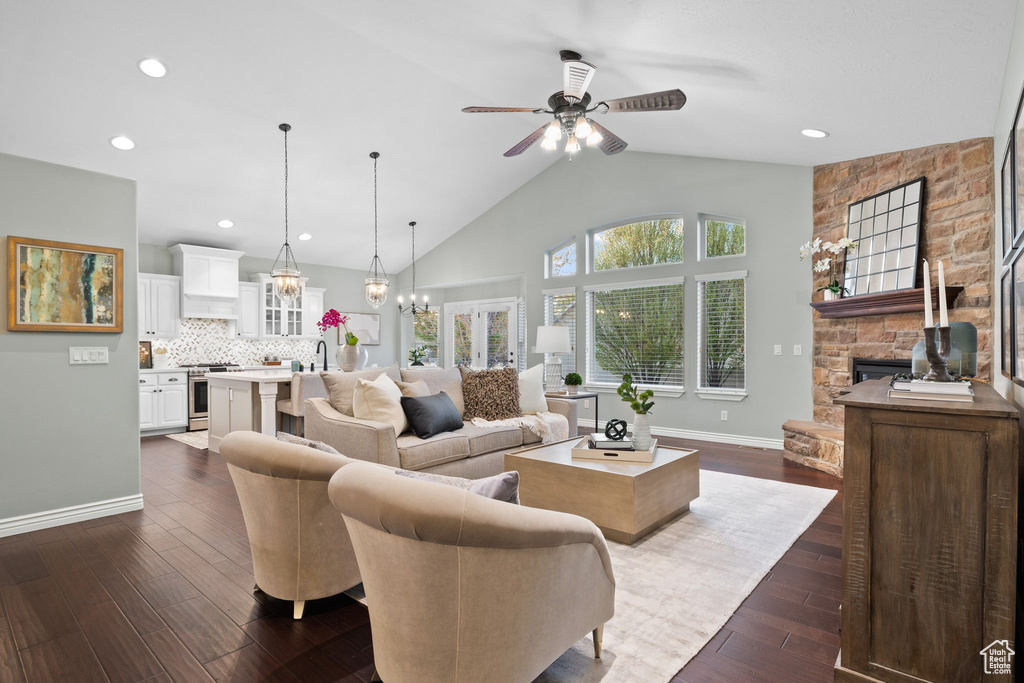 Living room with dark wood finished floors, baseboards, recessed lighting, ceiling fan with notable chandelier, and a fireplace