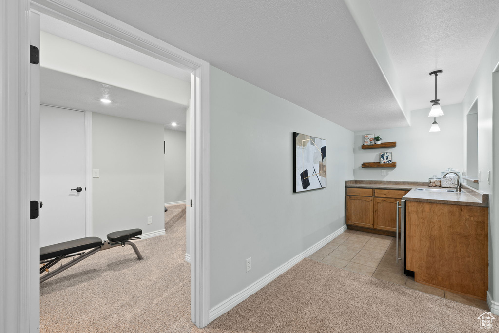 Interior space featuring baseboards, pendant lighting, a sink, and light colored carpet