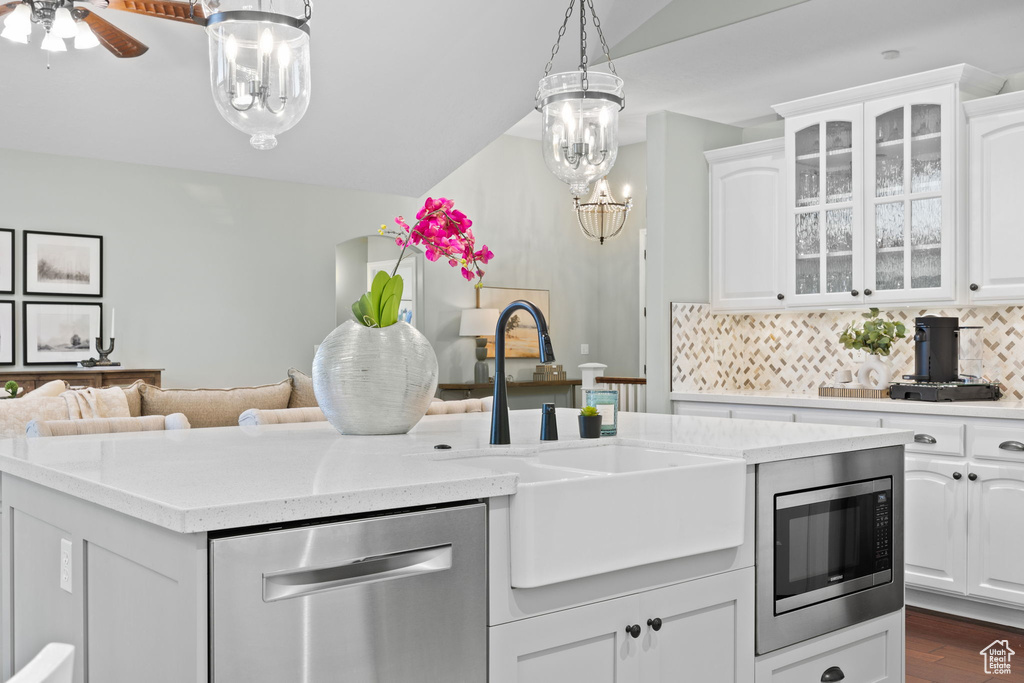 Kitchen with glass insert cabinets, white cabinetry, stainless steel appliances, and a sink