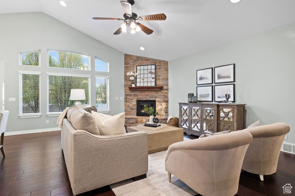 Living area with a stone fireplace, ceiling fan, lofted ceiling, and dark wood-type flooring