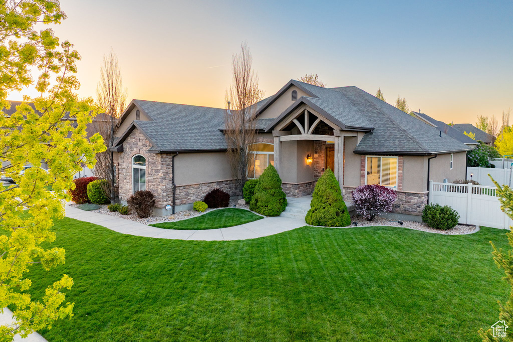 Craftsman house with stone siding, a front yard, and stucco siding