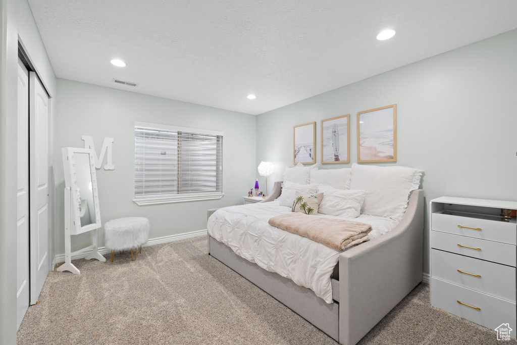Carpeted bedroom featuring baseboards, visible vents, recessed lighting, and a closet