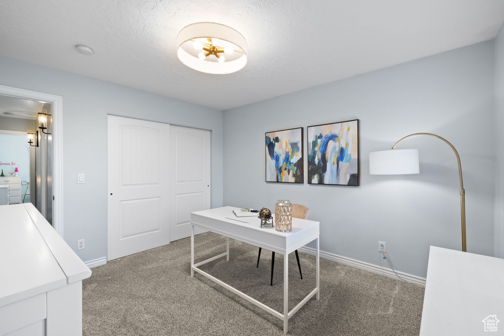 Carpeted home office featuring baseboards and a textured ceiling