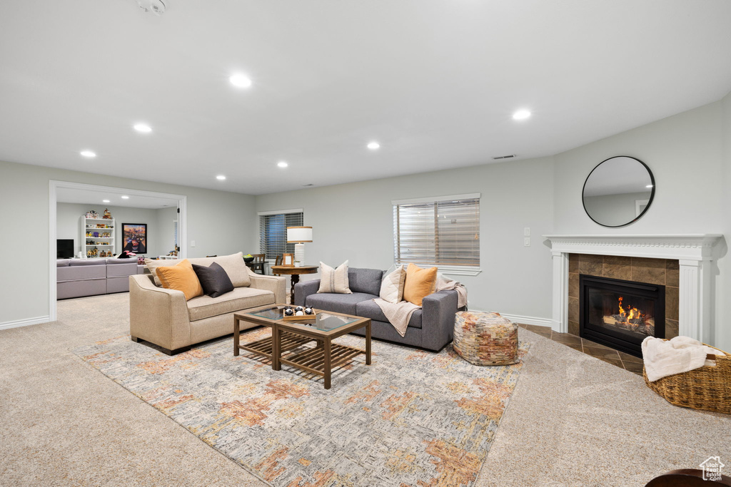 Carpeted living area with visible vents, a fireplace, baseboards, and recessed lighting