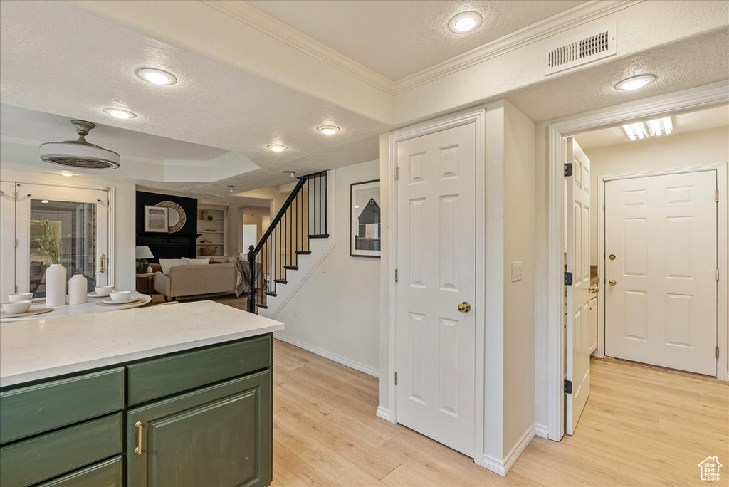 Interior space with crown molding, visible vents, stairway, and light wood-style floors