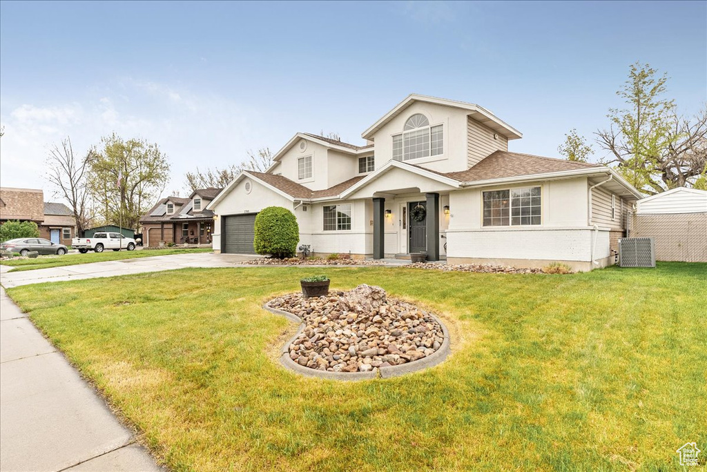 Traditional-style house with a garage, stucco siding, driveway, and a front yard