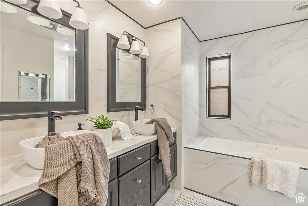 Full bathroom with double vanity and a tub with marble appearance