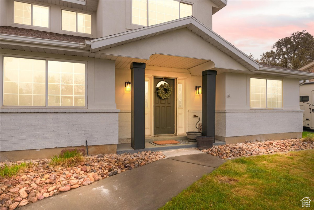 Exterior entry at dusk featuring brick siding and stucco siding