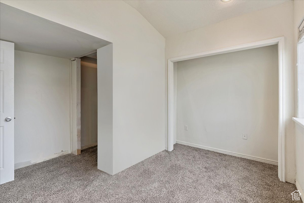 Carpeted spare room featuring lofted ceiling
