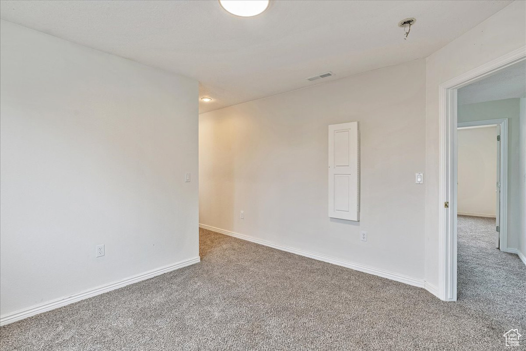 Carpeted spare room featuring visible vents and baseboards