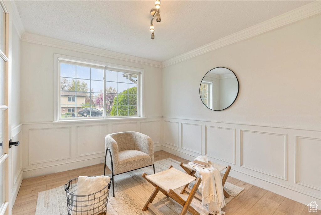 Living area featuring a wainscoted wall, light wood finished floors, and a decorative wall