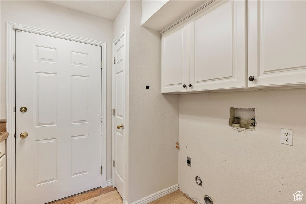 Laundry room with light wood-style floors, baseboards, hookup for an electric dryer, cabinet space, and washer hookup
