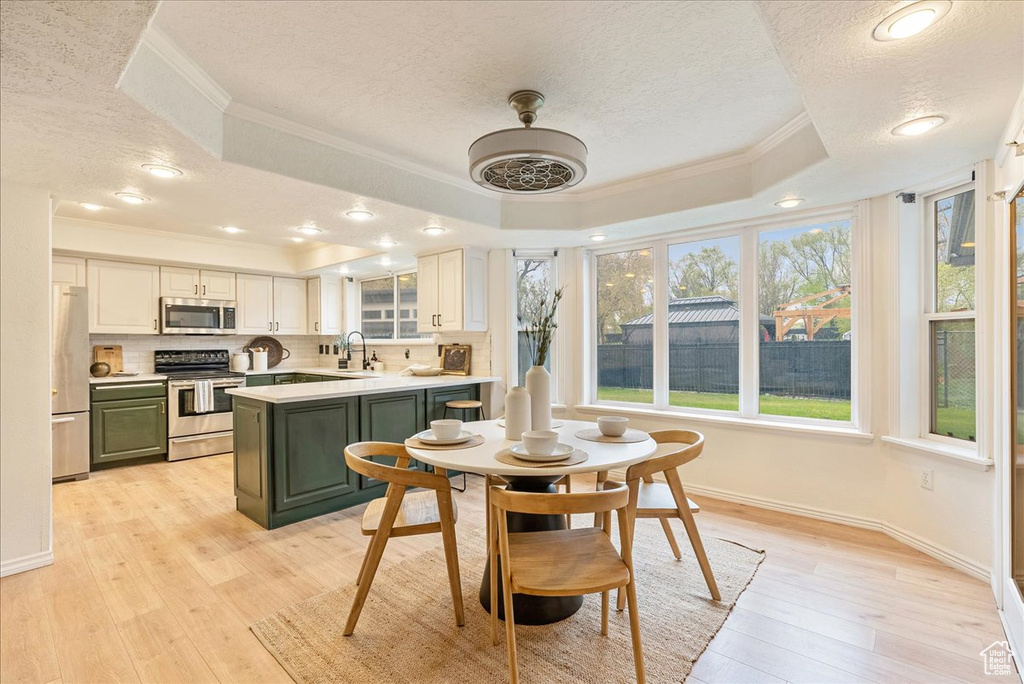 Interior space with crown molding, light wood-style floors, a tray ceiling, and a textured ceiling