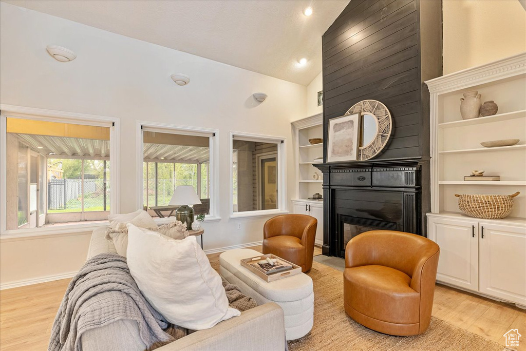 Interior space with light wood-style floors, baseboards, high vaulted ceiling, recessed lighting, and built in shelves