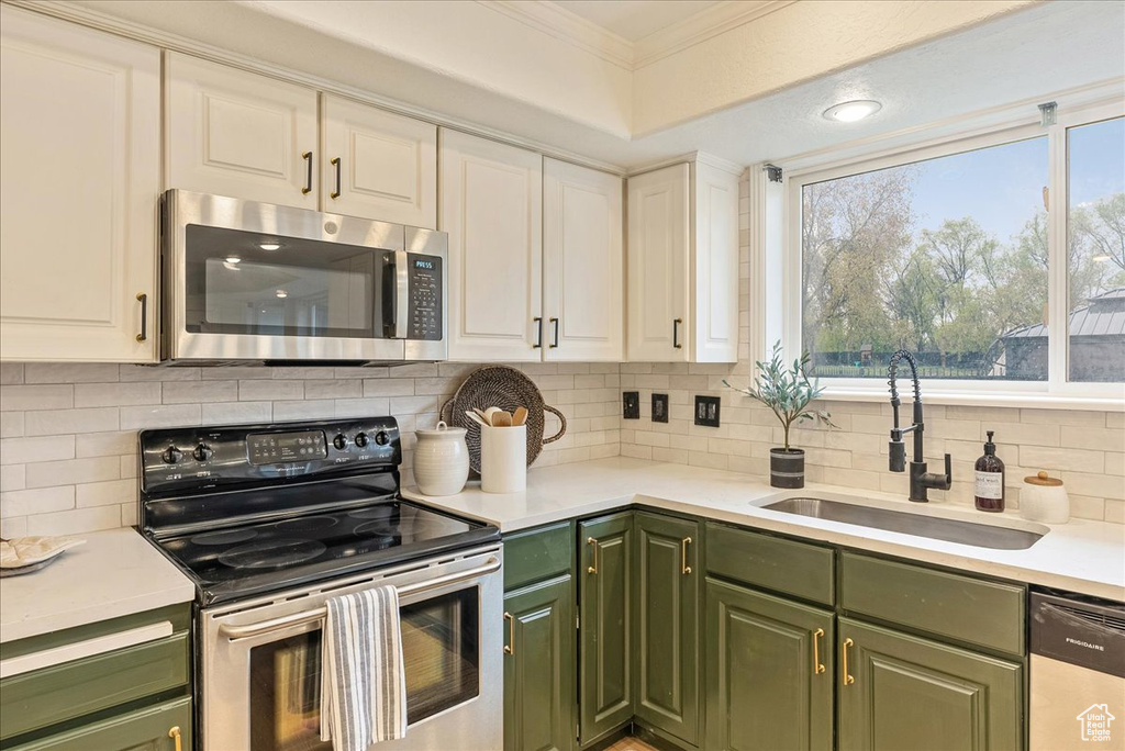 Kitchen with stainless steel appliances, green cabinetry, white cabinetry, and a sink