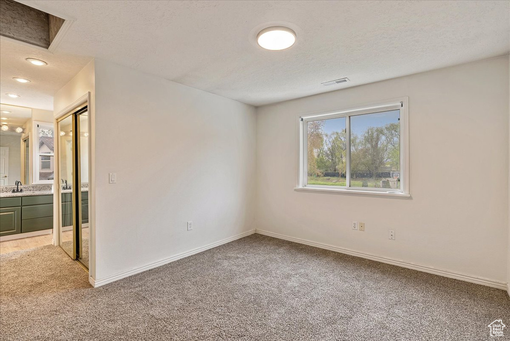 Unfurnished bedroom featuring a sink, baseboards, light carpet, and connected bathroom