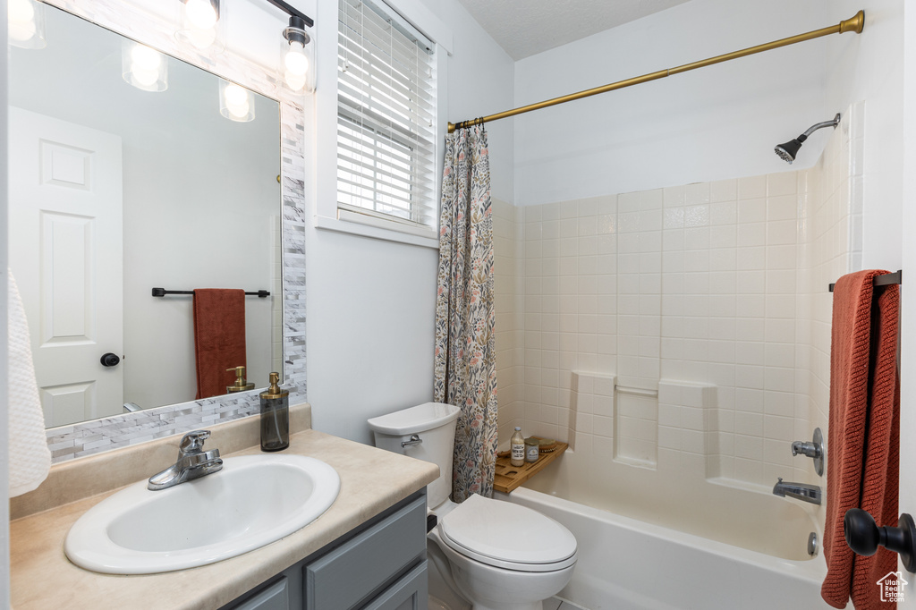 Bathroom with vanity, shower / bath combo, and toilet