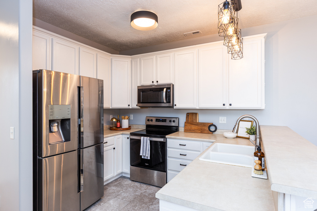 Kitchen featuring a sink, light countertops, stainless steel appliances, and white cabinetry