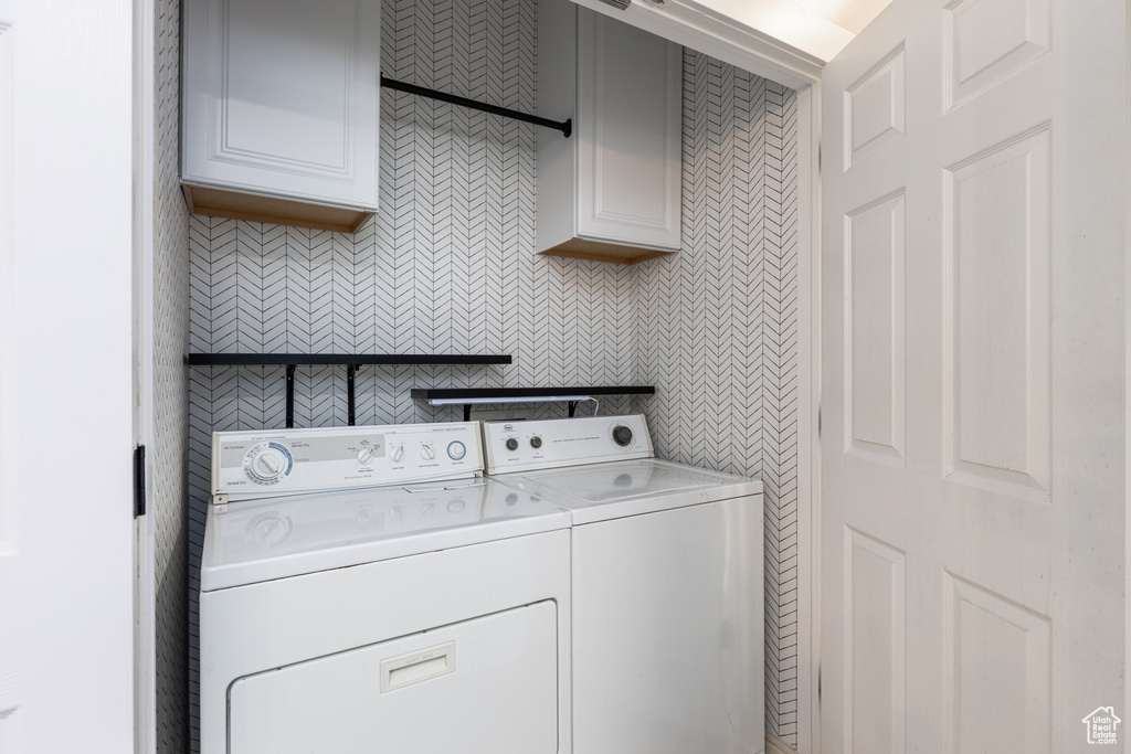 Washroom featuring cabinet space and separate washer and dryer