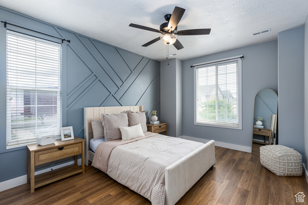 Bedroom with baseboards, a ceiling fan, wood finished floors, and visible vents
