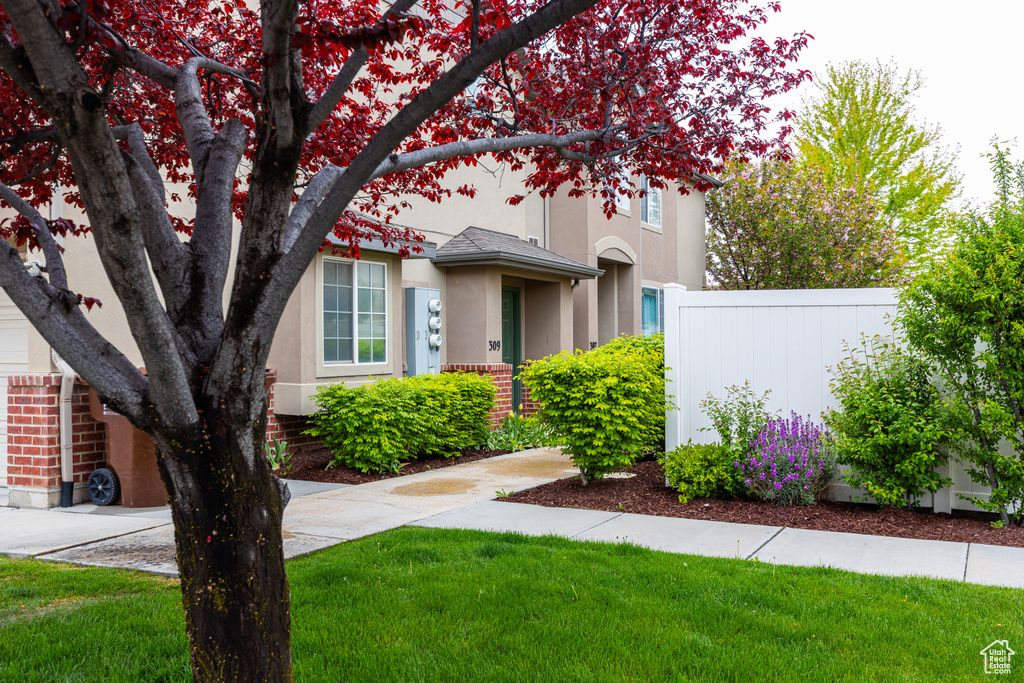 View of front of home featuring fence, stucco siding, a front lawn, and brick siding